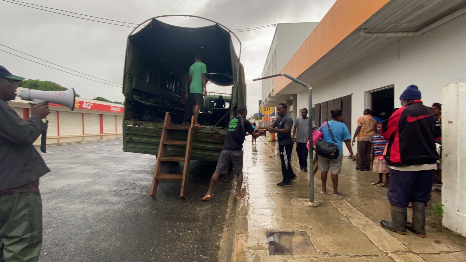 A truck is parked outside a building where people wait to be evacuated as part of the humanitarian support deployed after Tropical Cyclone Harold hit Vanuatu