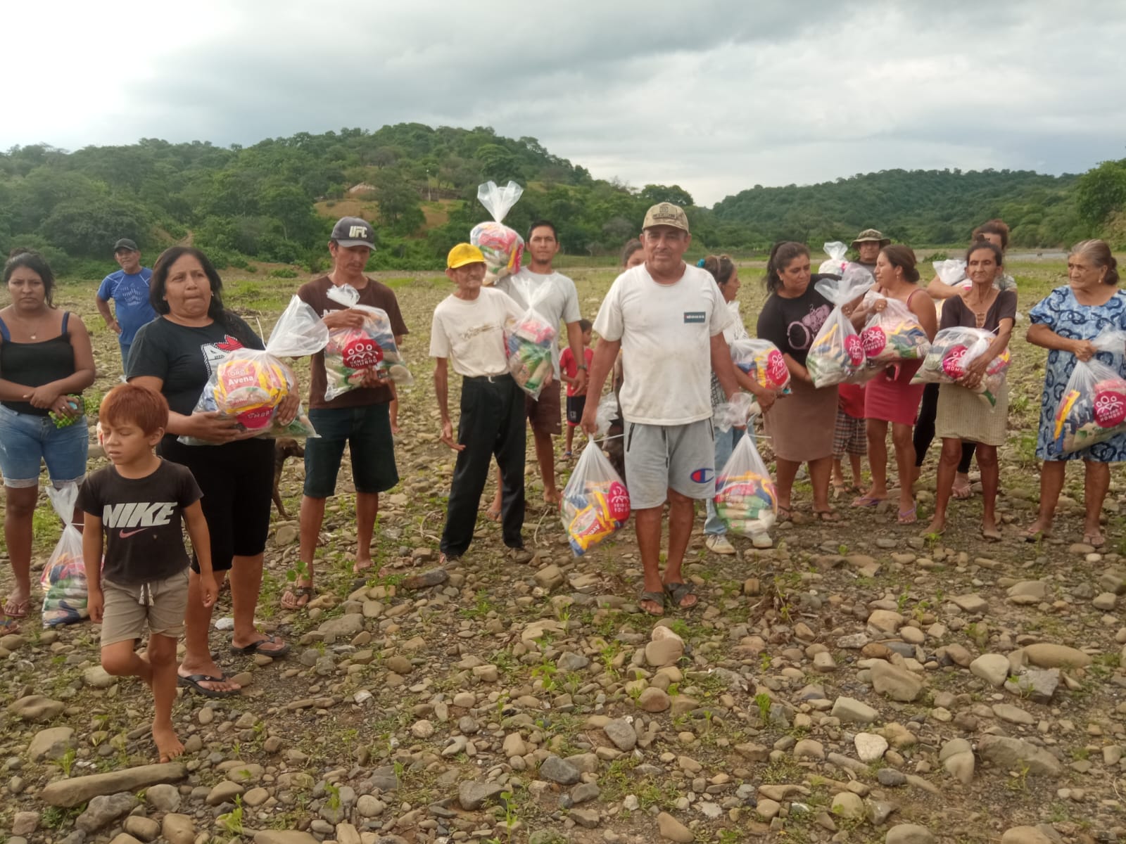 A group of people stand together holding bags with supplies distributed as part of Hombro a Hombro's humanitarian aid support in response to rainfall and dengue in rural Peru